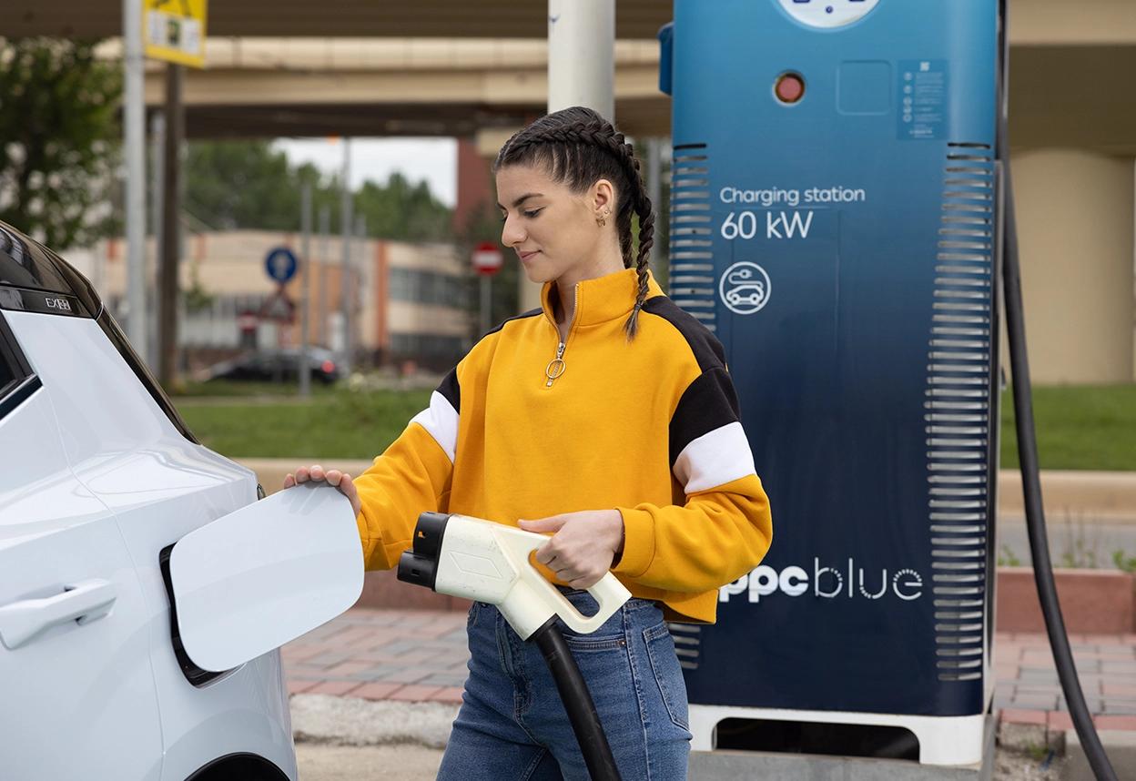 Femeie care conectează pompa de încărcare la mașina electrică