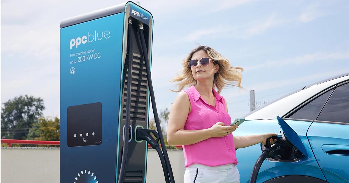 Femeie care își încarcă mașina electrică la o stație de încărcare PPC blue